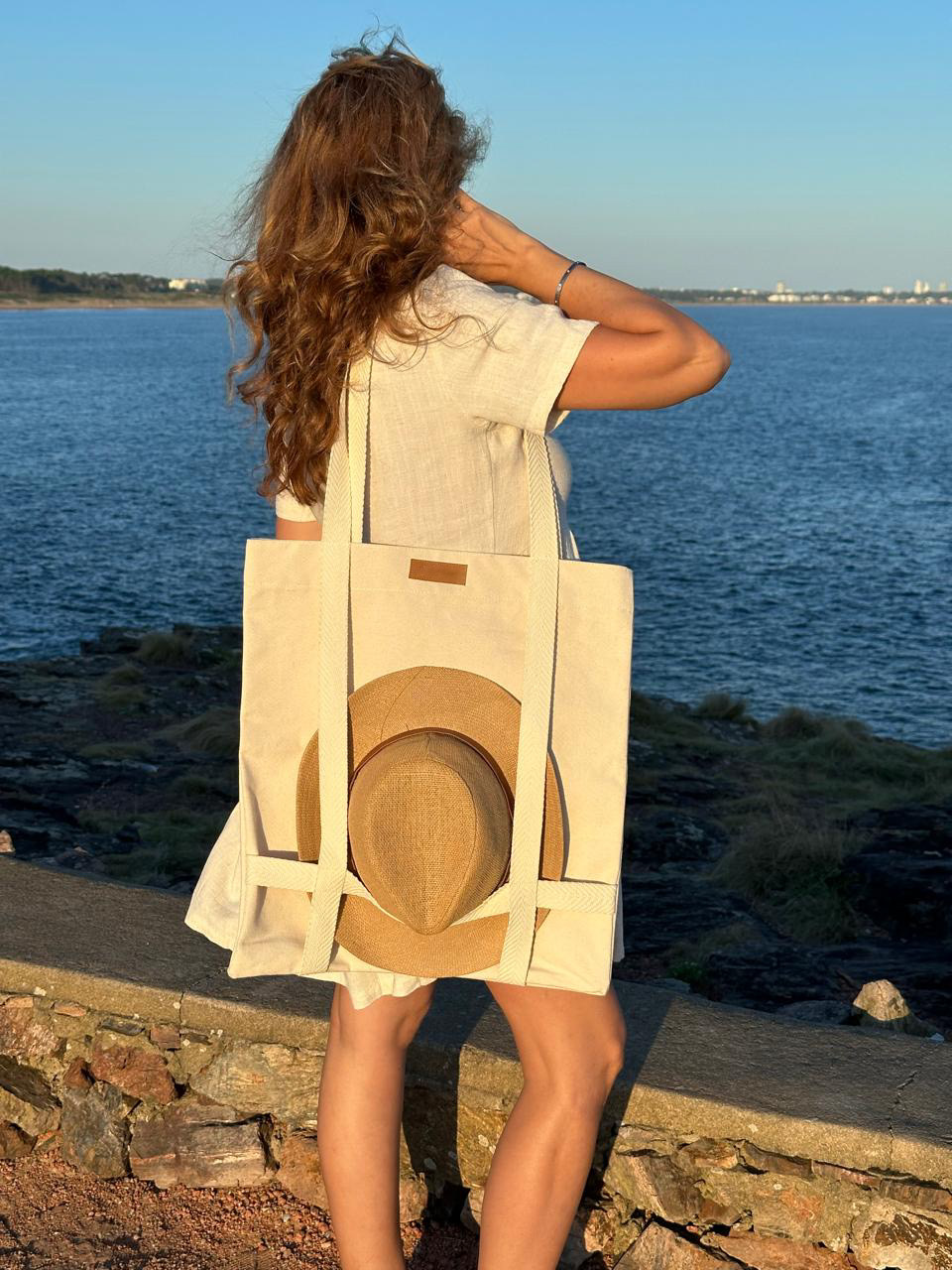 Bolso de tela con sombrero llevado junto a la costa
